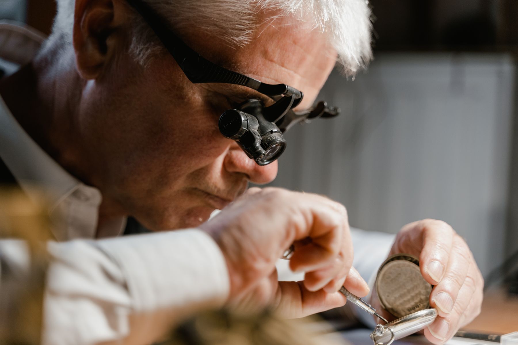 Clockmaker examining a pocket watch through a loupe